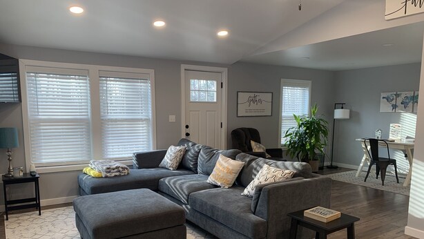 A modern living room with a sectional sofa, ottoman, and a small table.