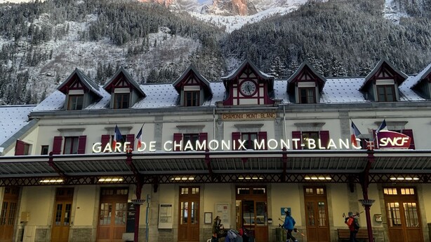Ein Hotel namens „Gare de Chamonix Mont-Blanc“ mit einem Glockenturm, verschneiter Umgebung und Berbgrund.