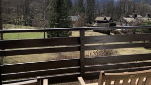 Eine Holzterrasse mit zwei Adirondack-Stühlen, die auf eine Berglandschaft ausgerichtet sind.