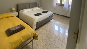 Un dormitorio con dos camas, una lámpara en el techo, una ventana con cortinas y un radiador.