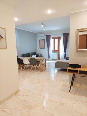 A spacious living area with a dining table and chairs, a sofa, and a small desk.