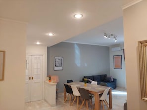 Un comedor con una mesa y sillas, un sofá y una kitchenette con mostrador y armarios.