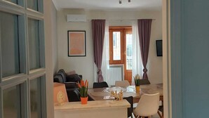 Un espacio abierto que combina sala de estar y comedor, con sofá, mesa de comedor, sillas y una pequeña cocina.