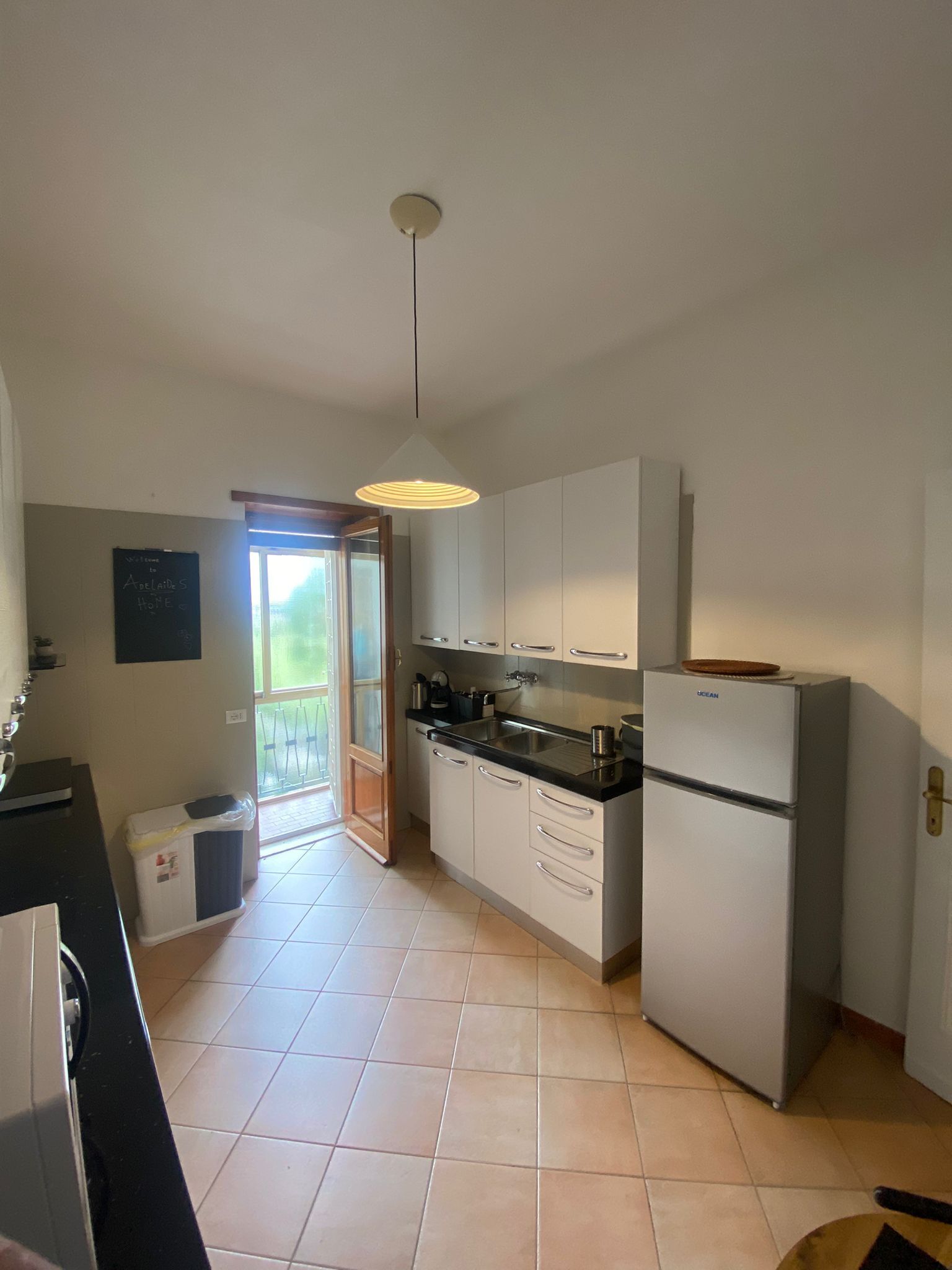 A compact kitchen with white cabinets, a black countertop, and a white refrigerator.