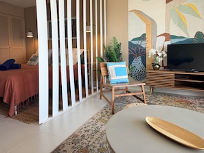 A modern living room with a sofa, a coffee table, a TV, and a decorative wall.