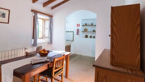 A dining area with a wooden table, chairs, a bowl of fruit, and a window with curtains. - Authentic apartment (Sineu)