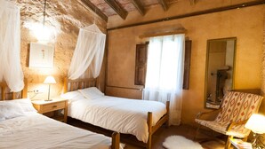 A rustic bedroom with two beds, a wooden headboard, a mirror, and a chair. - Authentic apartment (Sineu)