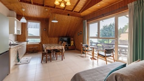 Een gezellig vakantiehuisje met een eethoek, keuken en een groot raam met uitzicht op de natuur.