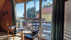 Een kamer met een grote schuifdeur die uitkomt op een terras buiten, met houten meubilair.