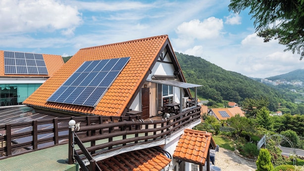 Een huis met een schuin dak, zonnepanelen en een houten balkon.