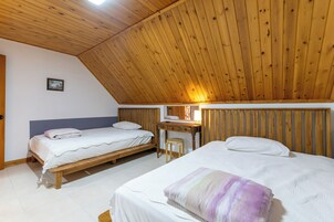 Una habitación con dos camas, techo de madera, una mesita y un espejo en la pared.