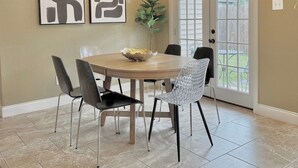 Un espace repas comprenant une table ronde, des chaises, un lustre et des œuvres d’art accrochées au mur.