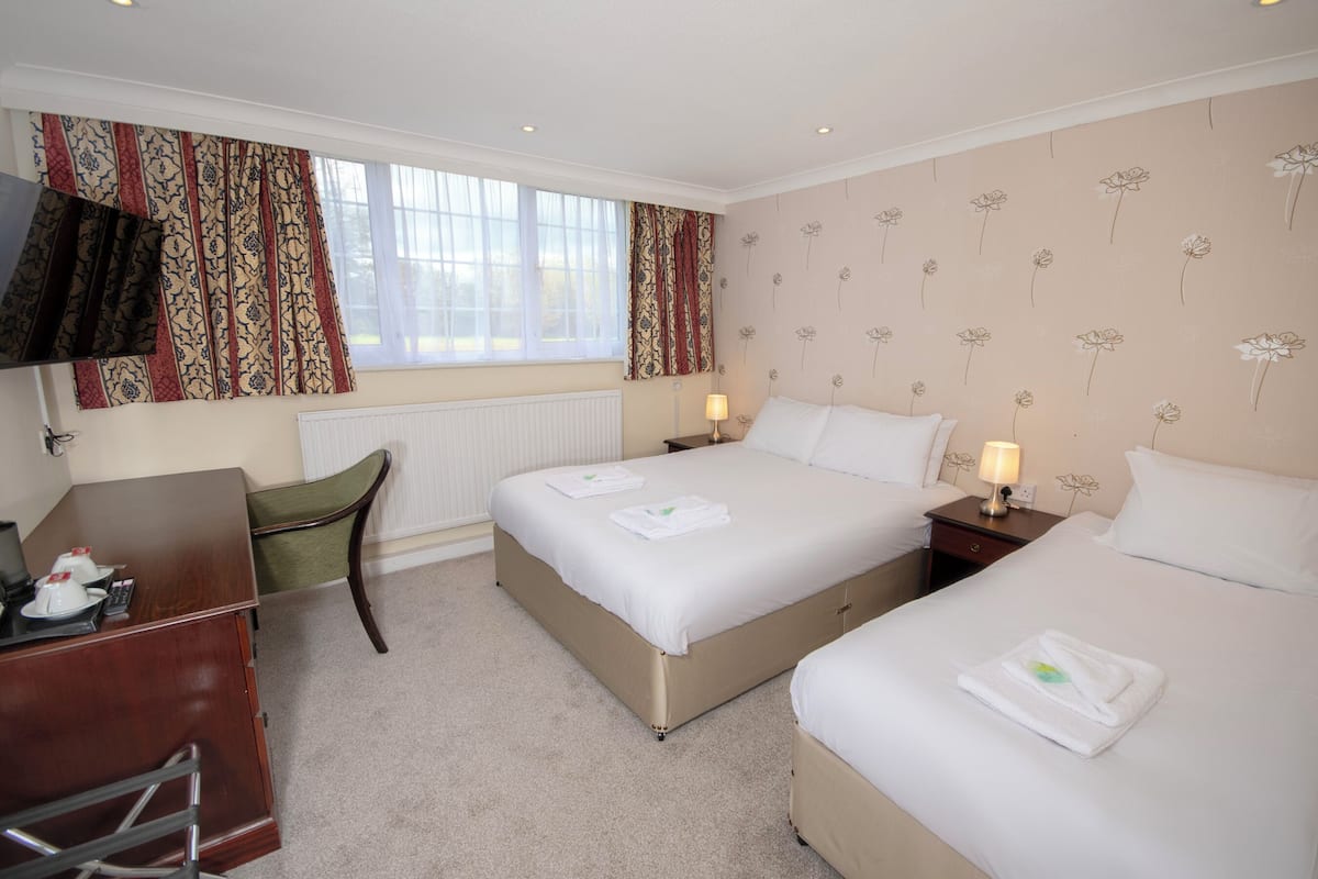 A hotel room with two beds, a desk, and a chair.