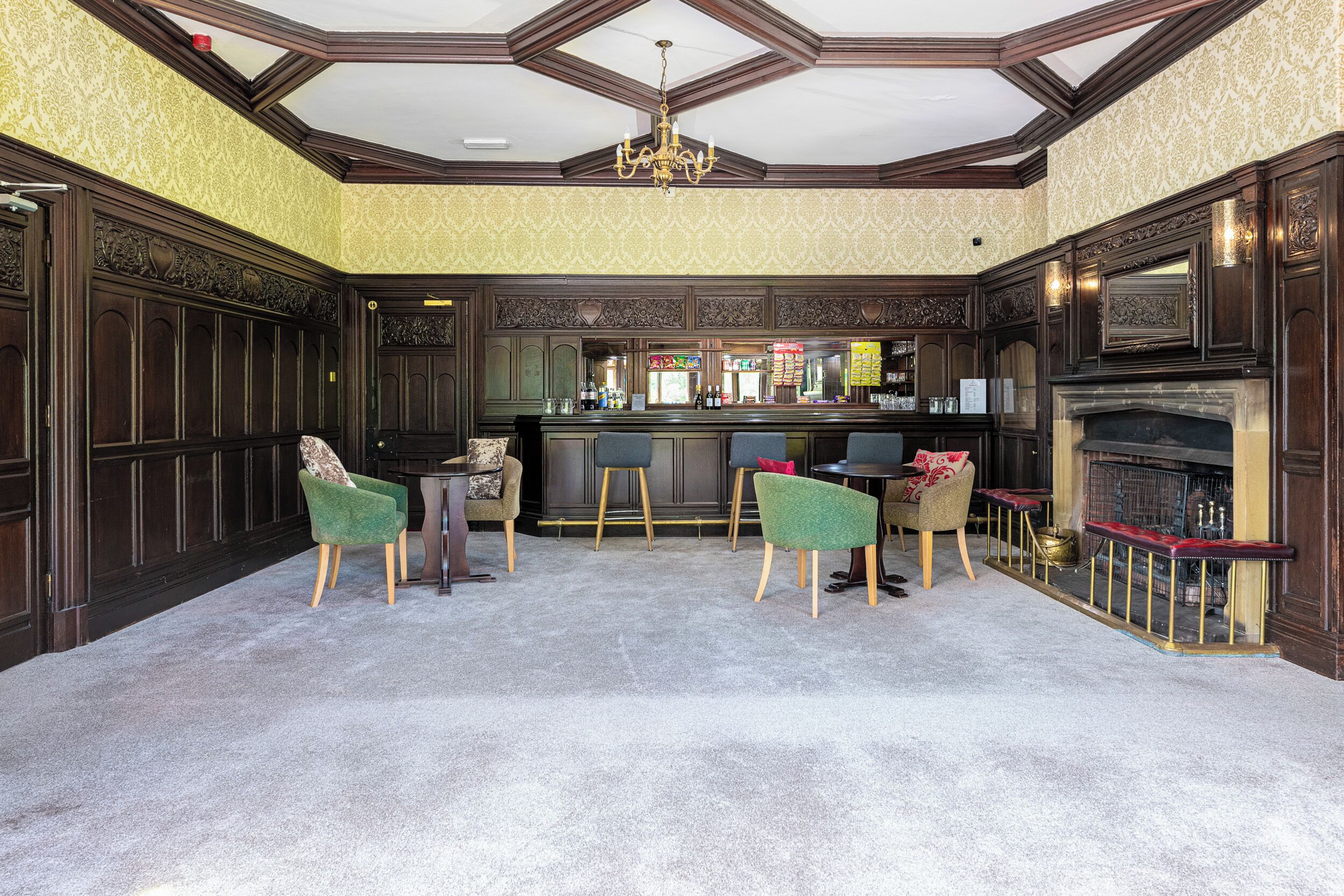 A bar area with a high ceiling, ornate wood paneling, and a fireplace.