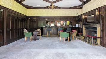 A bar area with a high ceiling, ornate wood paneling, and a fireplace.