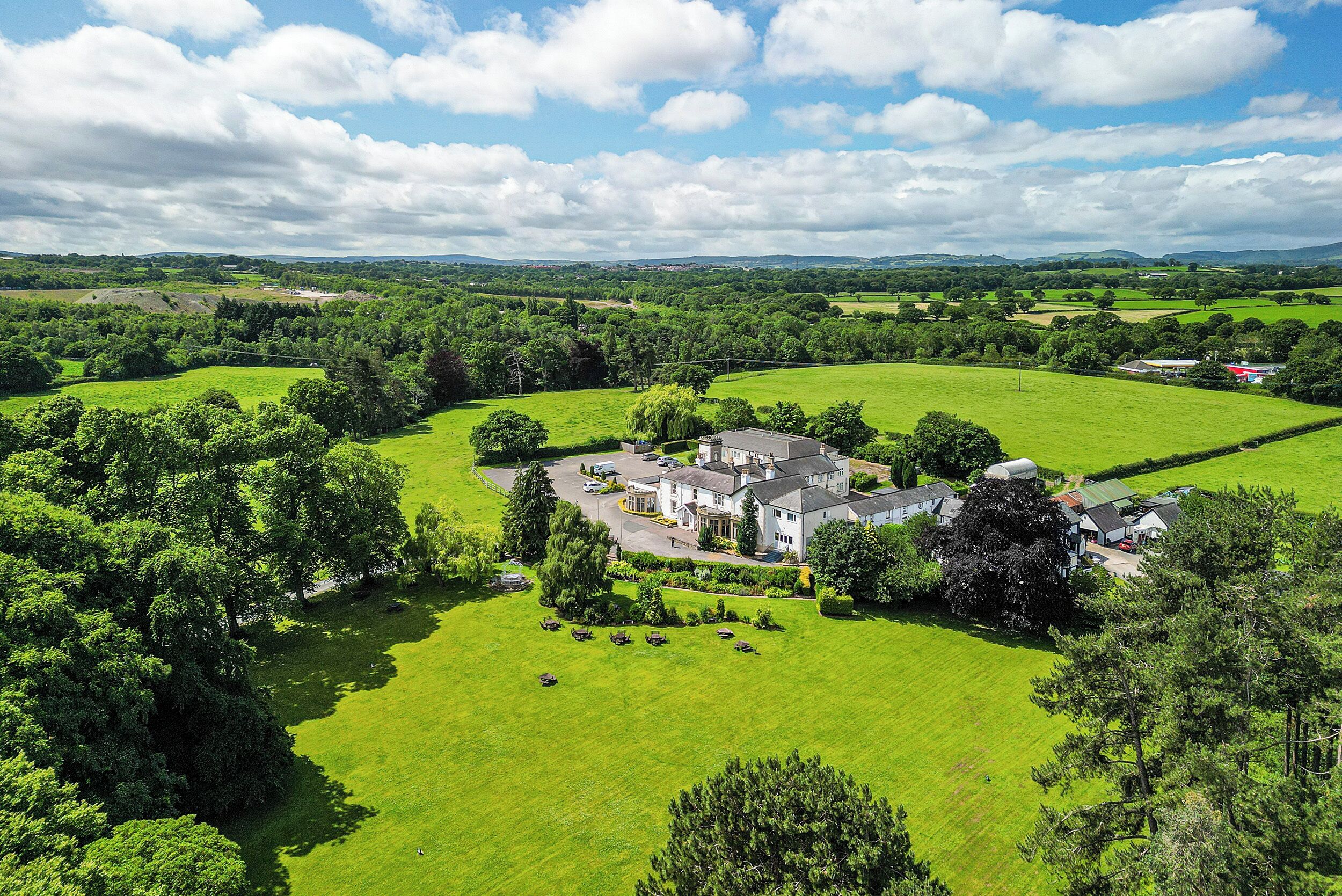 A large estate with multiple buildings surrounded by expansive green fields and trees.