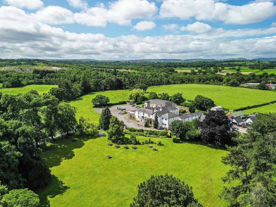 A large estate with multiple buildings surrounded by expansive green fields and trees.