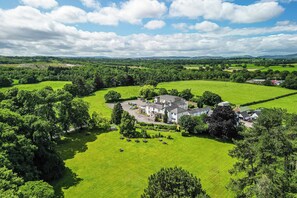 A large estate with multiple buildings surrounded by expansive green fields and trees. - Northop Hall Hotel (Mold)