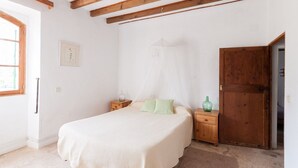 A bedroom with a bed, bedside tables, a wardrobe, and a window. - Family apartment Ca l'Amo (Sineu)