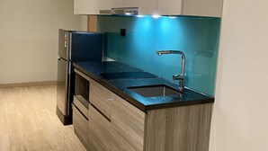 Eine moderne Küche mit einem Edelstahlkühlschrank, einer schwarzen Arbeitsplatte, einer Spüle und Holzschränken.