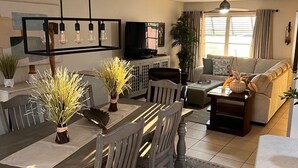 A modern living room with a dining area, a flat-screen TV, and a ceiling fan. - New on Market ! Beautiful family home close to beach, golf, tennis and shopping. (Venice)
