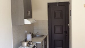 A compact kitchen with a stove, sink, and cabinets. - Elena Rooms (Agios Vasileios)