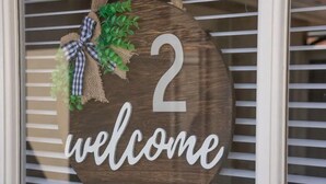Een houten bord met het cijfer 2 en de tekst 'welcome' op een raam.