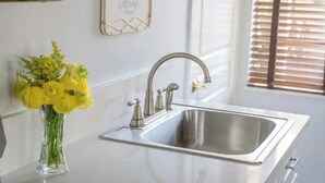 Een moderne keuken met een roestvrijstalen spoelbak, een vaas met gele bloemen en een welkomstbord aan de muur.