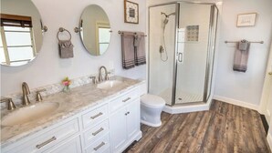 Een badkamer met twee wastafels, een toilet en een douche met glazen wanden.