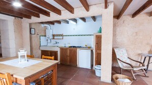 Una cocina rústica con vigas de madera, una mesa de comedor con sillas, un refrigerador y un lavamanos.