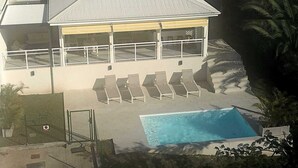 En toetagers bygning med en swimmingpool, liggestole og en overdækket patio.