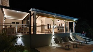 Et moderne hus med en overdækket terrasse, udendørs møbler og en swimmingpool.