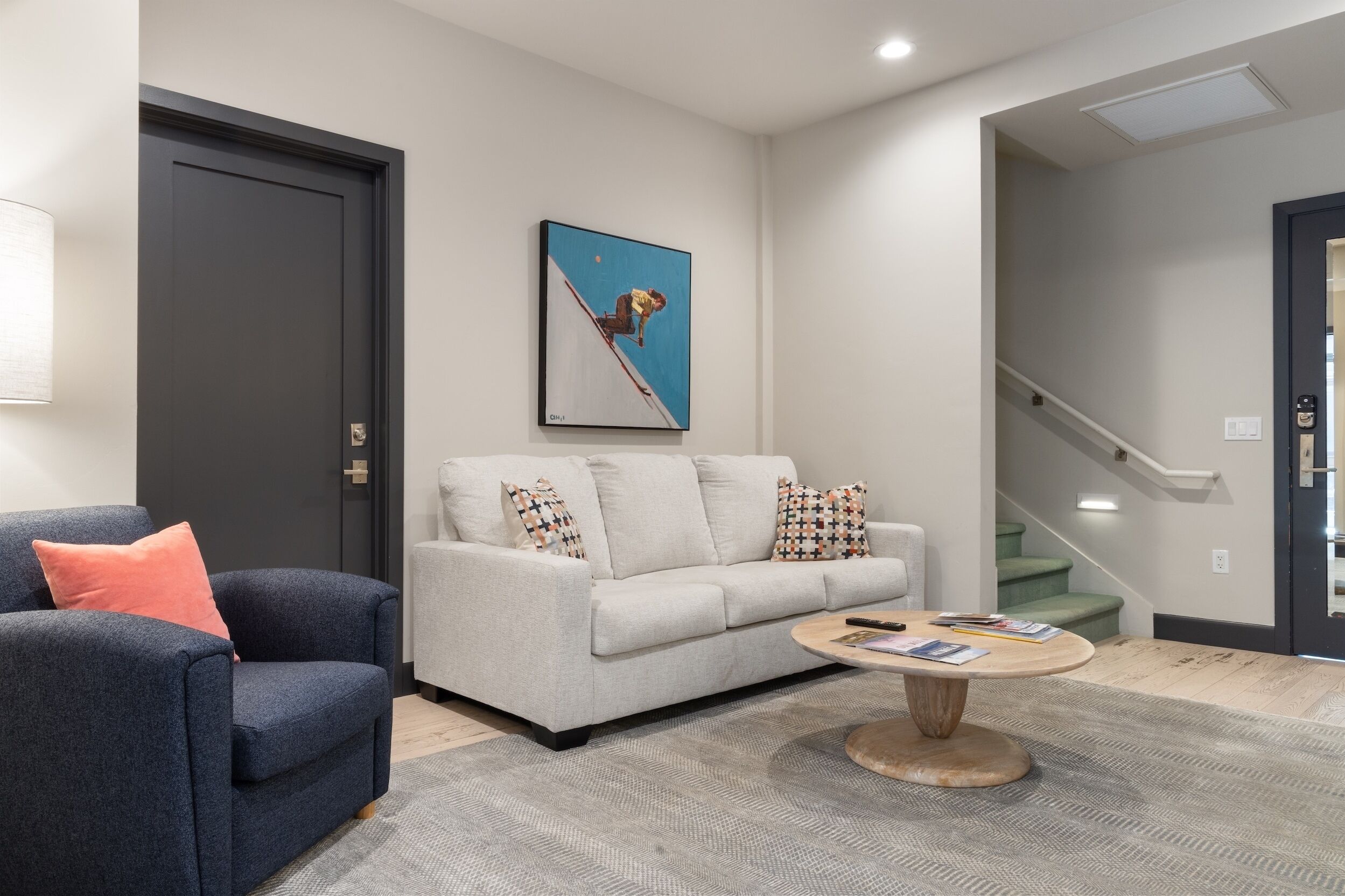 A modern living room with a grey sofa, a blue armchair, and a coffee table.