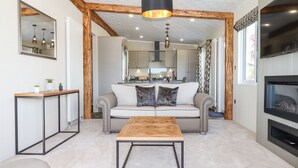 A modern living room with a sofa, coffee table, and fireplace. - Cherry Lodge (Newton Abbot)