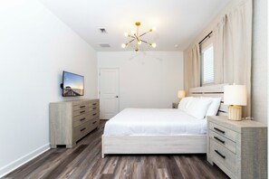 Ein Schlafzimmer mit Bett, Nachttischen, einem Schminktisch, einer Deckenleuchte und einem Bild an der Wand.
