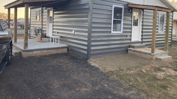 A single-story mobile home with a covered porch and a small patio area. - Fern’s Cottage New Construction! A cozy place to relax. (Atmore)