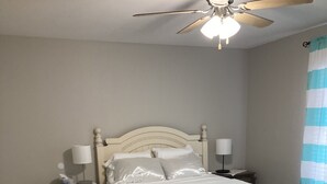 A bedroom with a bed, nightstands, a ceiling fan, and a window with curtains. - Fern’s Cottage New Construction! A cozy place to relax. (Atmore)