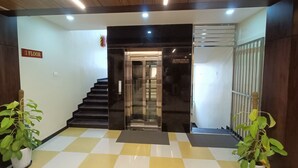 A hotel lobby with a checkered floor, a staircase, and a sign indicating the second floor. - Sri Aswin Grand (Namakkal)