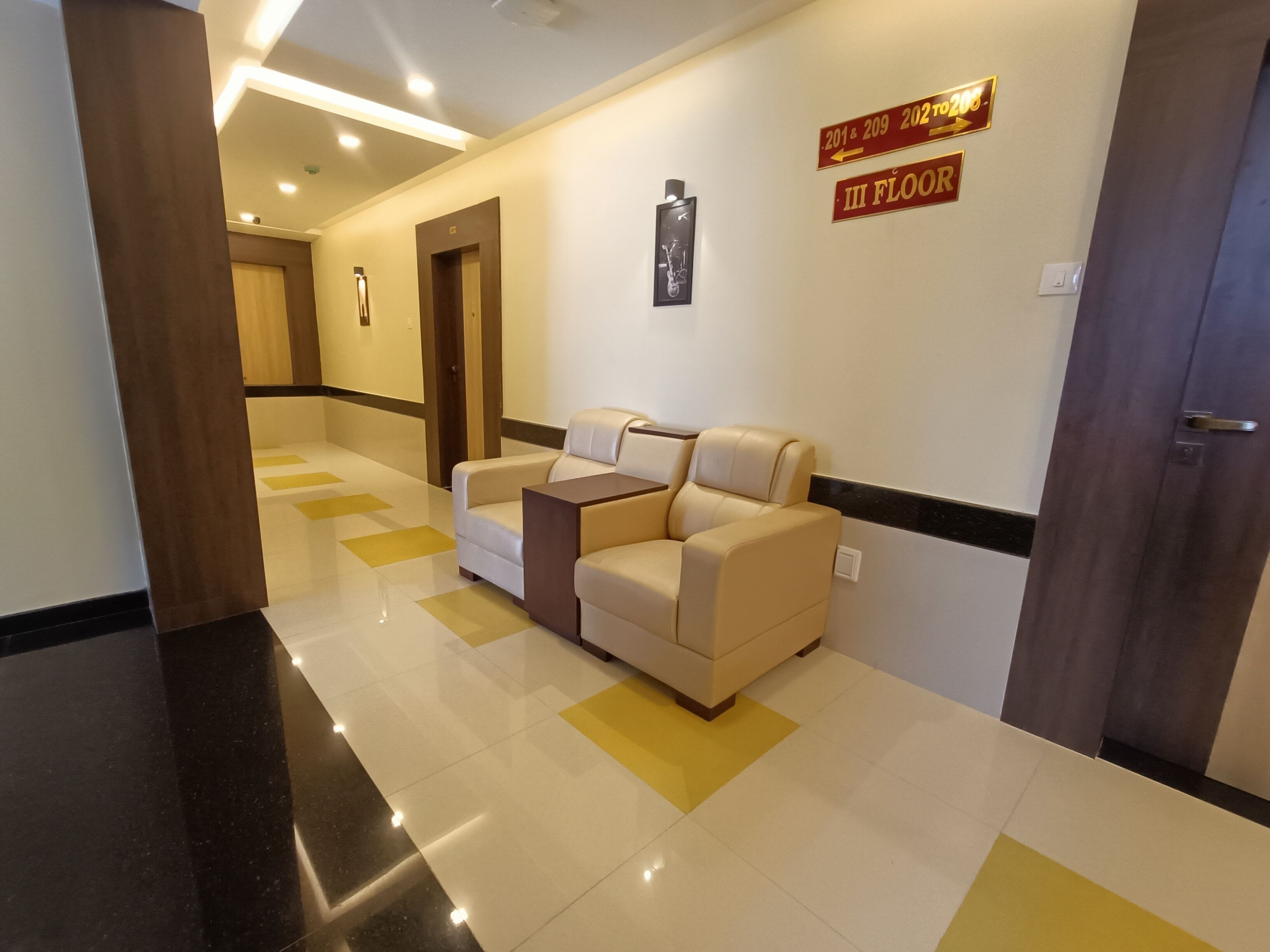 A hotel lobby with a reception area, a sofa, a coffee table, and a sign indicating the third floor.