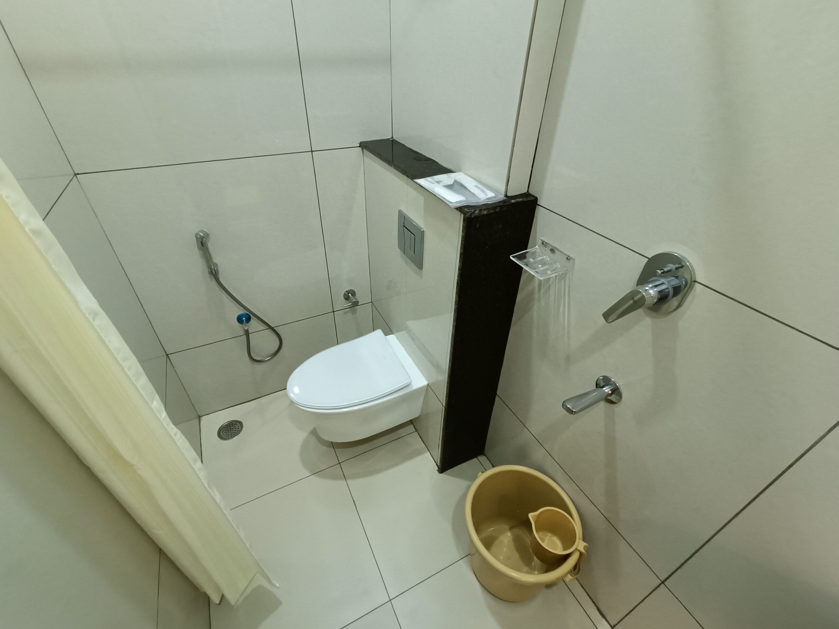 Un baño con inodoro, ducha, lavabo y un balde.