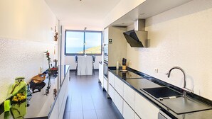Una cocina moderna con vista al mar, un comedor y un baño.