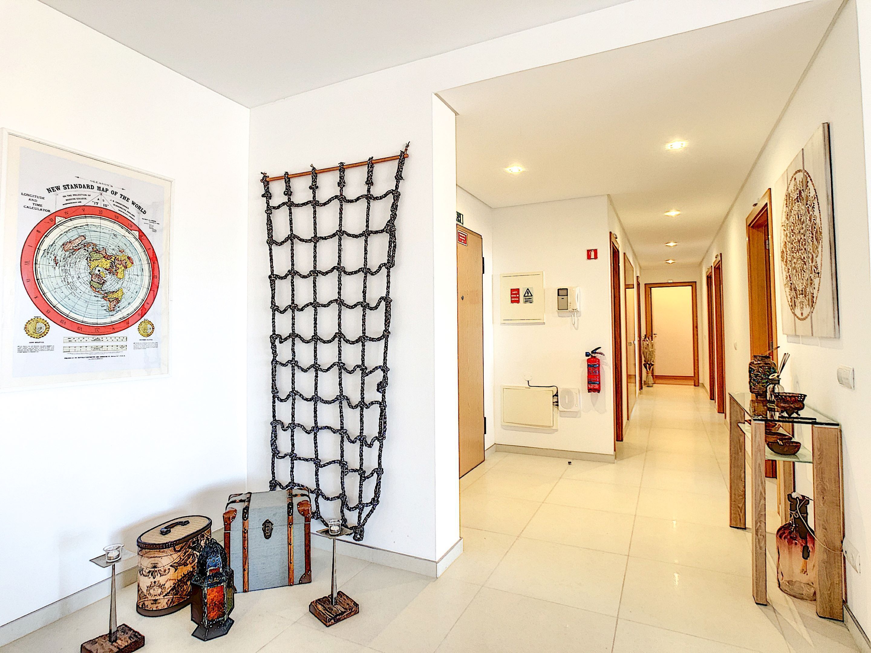 A hallway with a map, a net-like decoration, and vintage suitcases.
