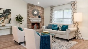A living room with a fireplace, two white sofas, a coffee table, and a floor lamp. - Super Cozy Entire House. Close to Everything (Katy)