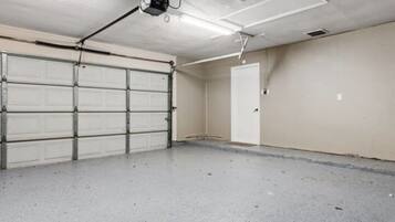 Un garage avec une porte blanche, un ventilateur de plafond et un éclairage fluorescent.