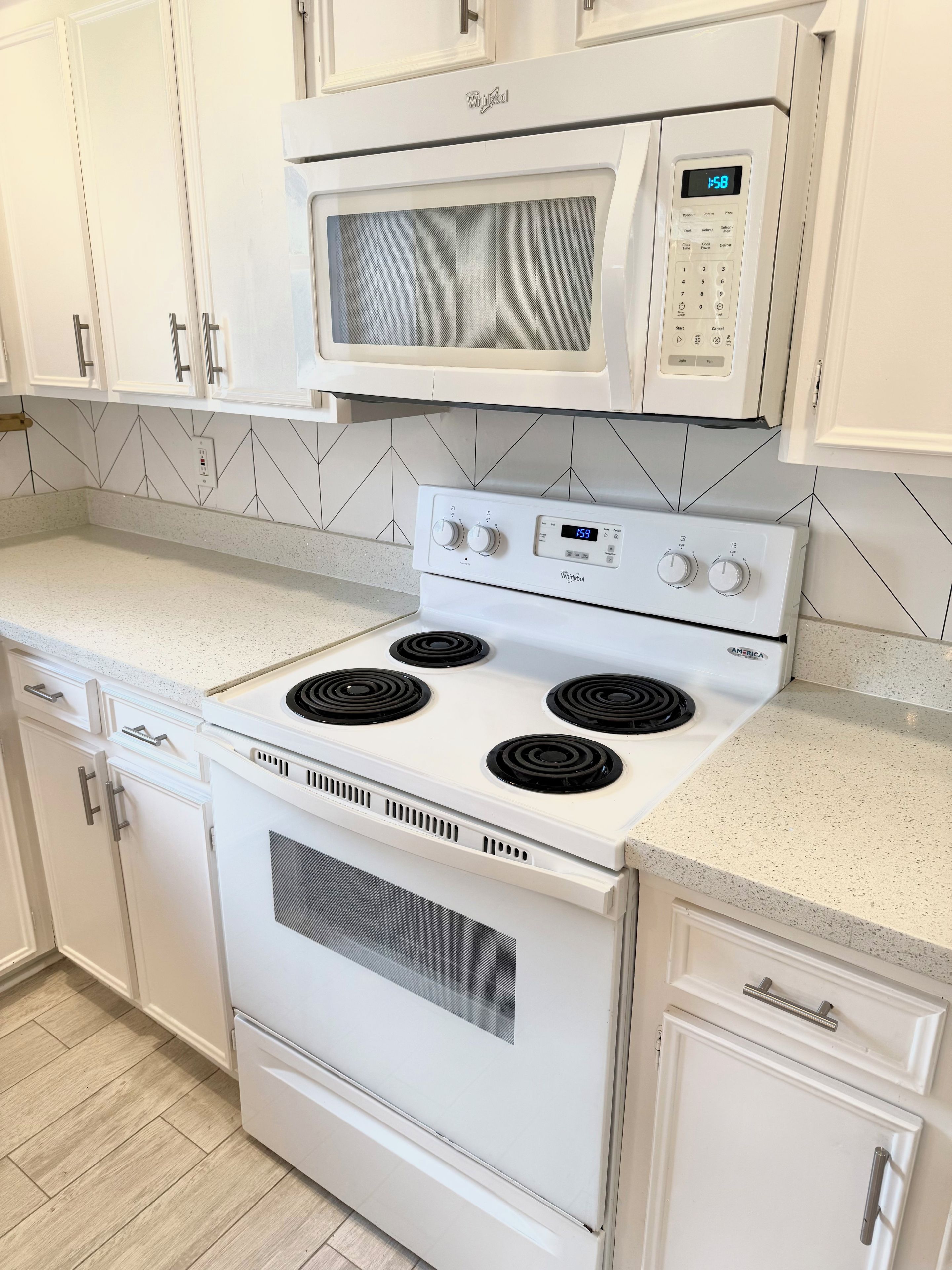 A kitchen with a white stove, oven, and microwave, and white cabinetry.
