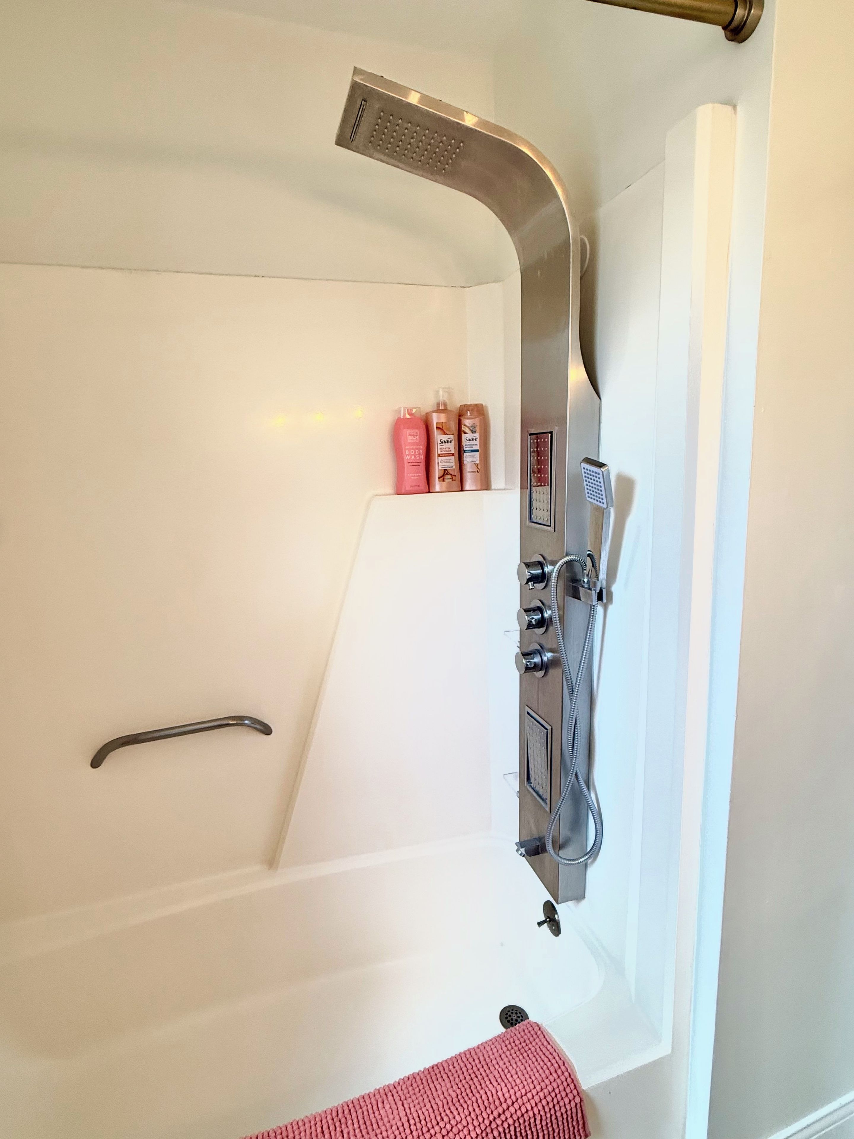 Ein modernes Badezimmer mit einer weißen Badewanne, einer Duschbrause und einer Zusammenstellung von Pflegeprodukten.