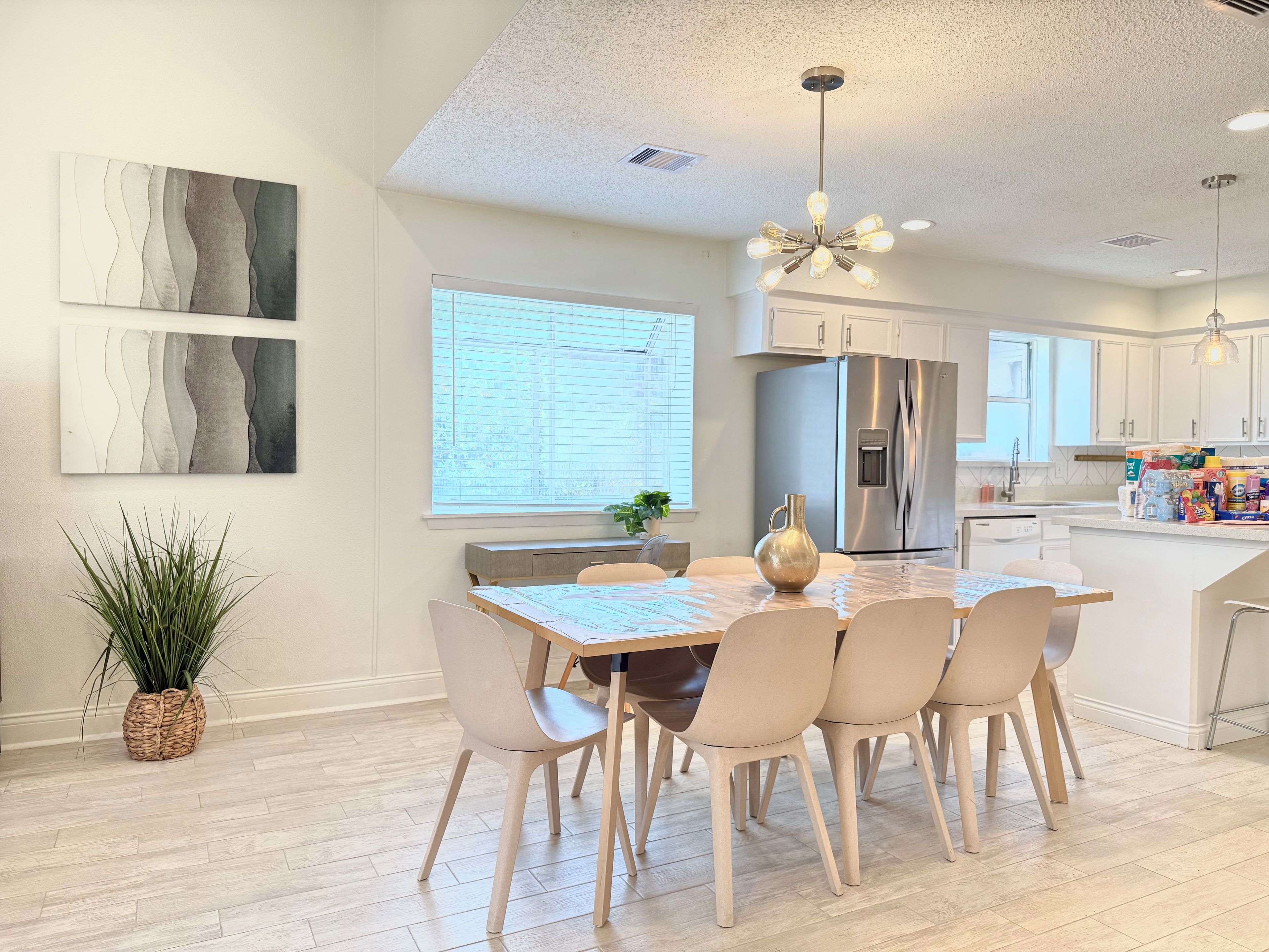 A modern kitchen with a central island, stainless steel appliances, and a dining area with a table and chairs.