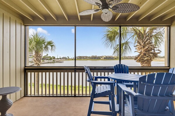 A balcony with a view of a body of water, palm trees, and a distant building.