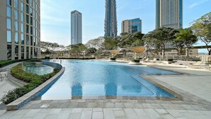 A swimming pool with lounge chairs and a view of tall buildings in the background.