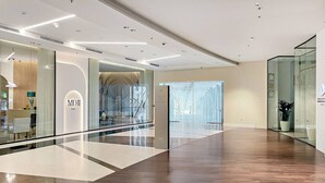 A modern interior with a glass facade, wooden flooring, and a reception area with a sign reading "MD11 HOME".